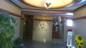 A lobby with a chandelier, a reception desk, a staircase, and a vase of sunflowers. - Golden Bee Motel (Gunsan)