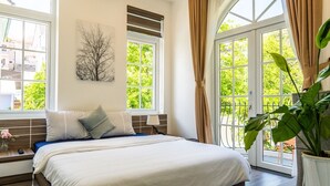 Quarto com cama grande, janela com persianas, obra de arte na parede e planta em vaso.