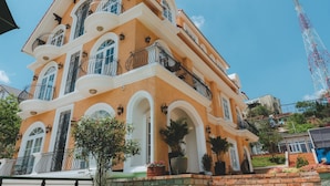 Um edifício de vários andares com varandas, janelas amplas e base de tijolos.