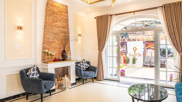 Um interior moderno com duas poltronas, uma mesa de vidro, lareira de tijolos e vista para o exterior.