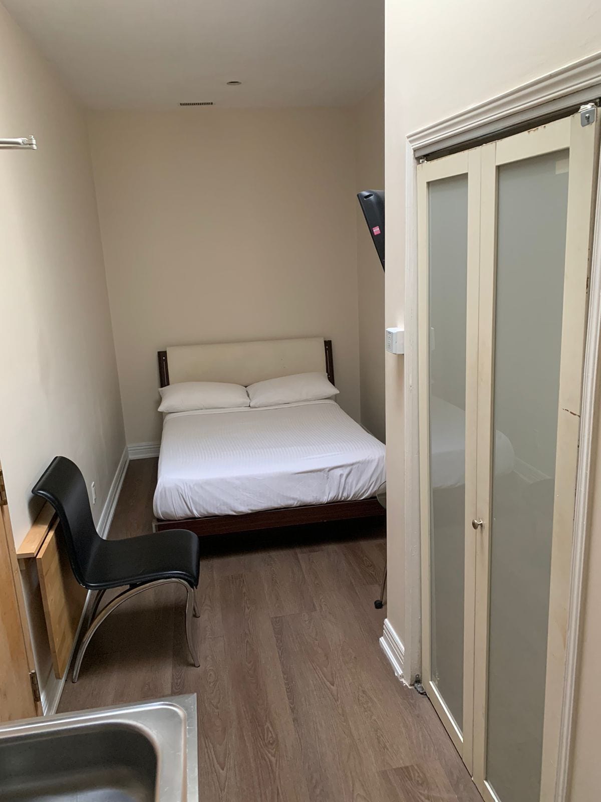 Ein kleines, gemütliches Schlafzimmer mit einem Bett, einem Sessel und einem Kleiderschrank.