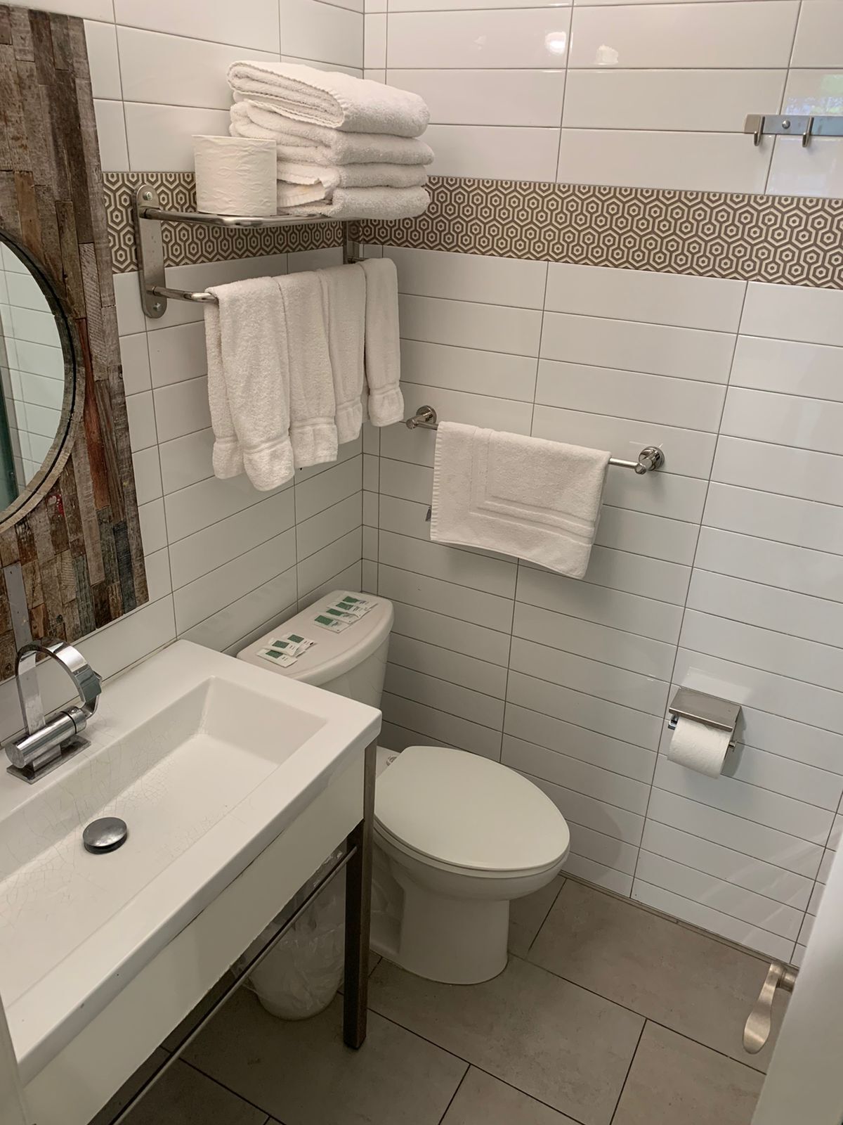 Un baño con un lavamanos blanco, un inodoro y un perchero con toallas dobladas.