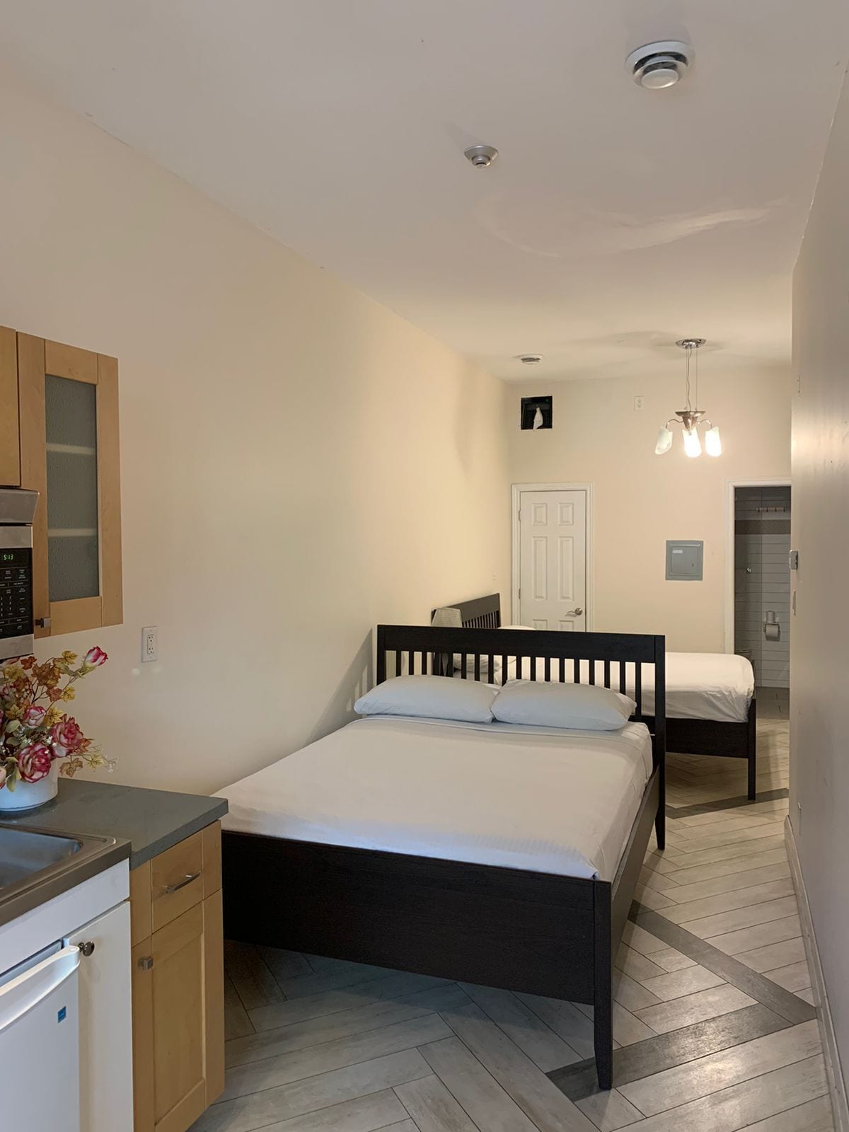 Un dormitorio con cama, escritorio, silla y una pequeña kitchenette.
