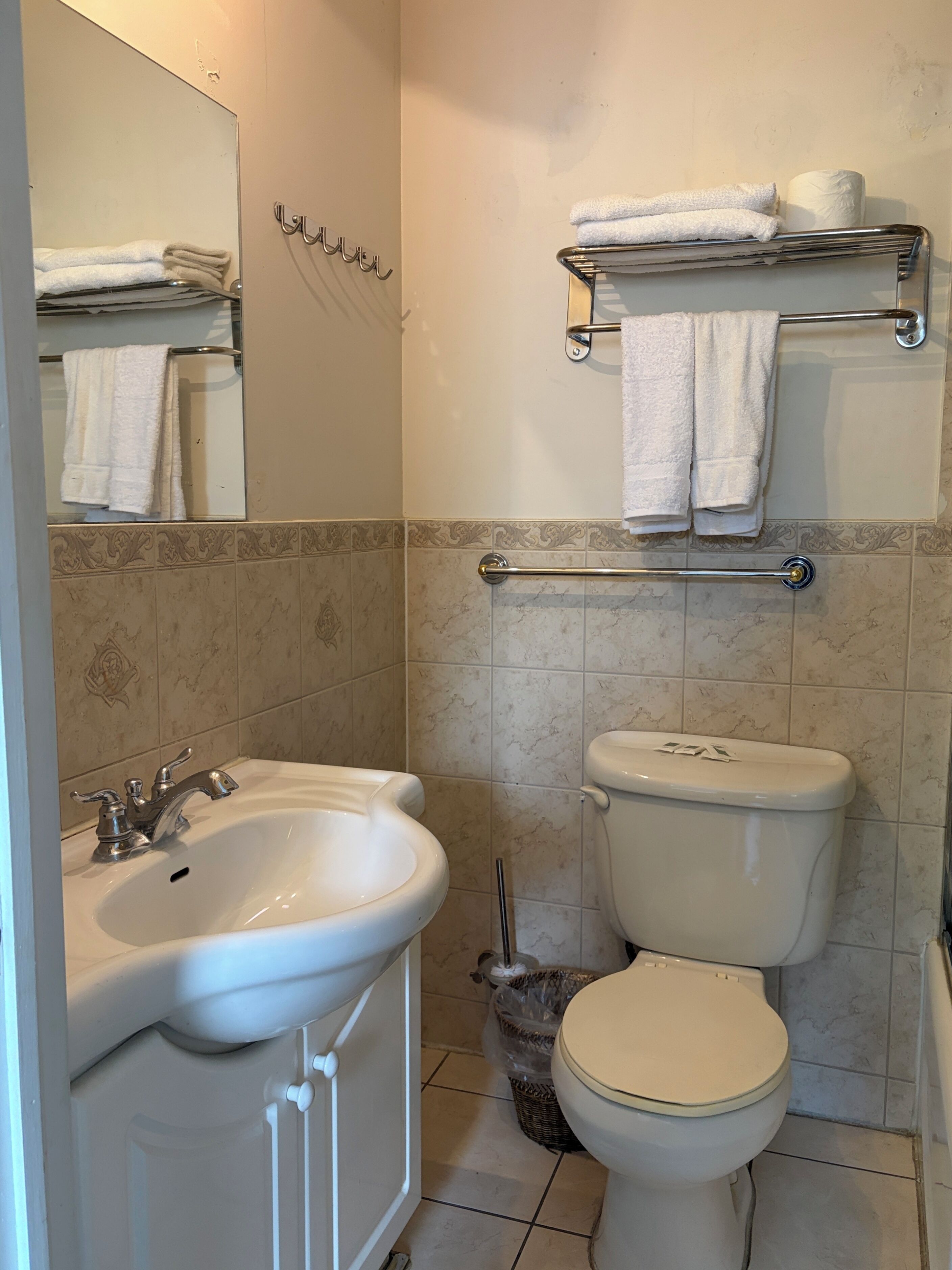 Une salle de bain équipée d’un lavabo, de toilettes, d’un porte-serviettes et d’un miroir.