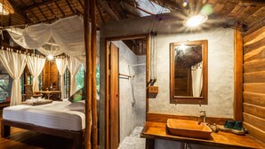 Un dormitorio tipo cabaña de madera con una cama, un baño con lavabo y espejo, y una ducha.