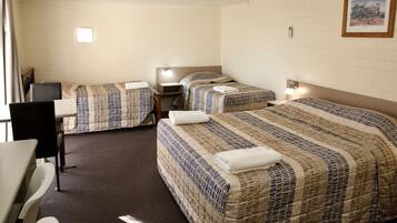 A hotel room with two single beds, a desk, a chair, and a small table.