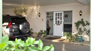 A covered parking area with a vehicle, a white door, and potted plants. - Pioneer Motel (Goondiwindi)