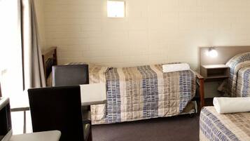 Habitación de hotel compacta con dos camas, un escritorio, una silla y un televisor.