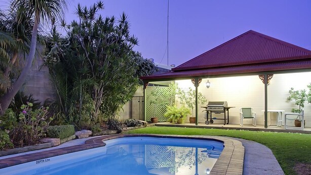 A swimming pool with a depth of 12m, surrounded by a well-maintained lawn and various plants. - Pioneer Motel (Goondiwindi)