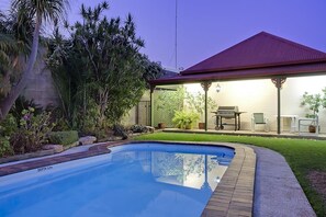 A swimming pool with a depth of 12m, surrounded by a well-maintained lawn and various plants. - Pioneer Motel (Goondiwindi)
