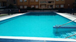 A rectangular swimming pool with a tiled edge, surrounded by a black metal fence. - Fantastic apartment (El Morche)