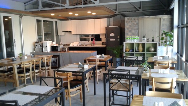 Um restaurante com várias mesas e cadeiras, uma área de cozinha e um bar.