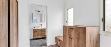 A modern bathroom with a wooden vanity, a white sink, and a mirror.