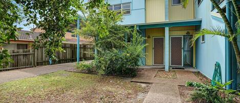 A residential building with a blue exterior, a covered porch, and a small garden area.