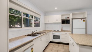 A modern kitchen with white cabinets, a double sink, a microwave, a stove, and a refrigerator. - COOLAMAINE 1 - Rainbow Beach. Easy walk to beach and shops. (RAINBOW BEACH)