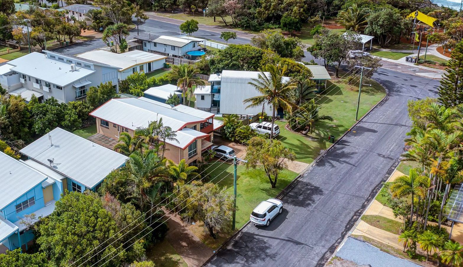 A residential area with houses, a road, and a view of the ocean.