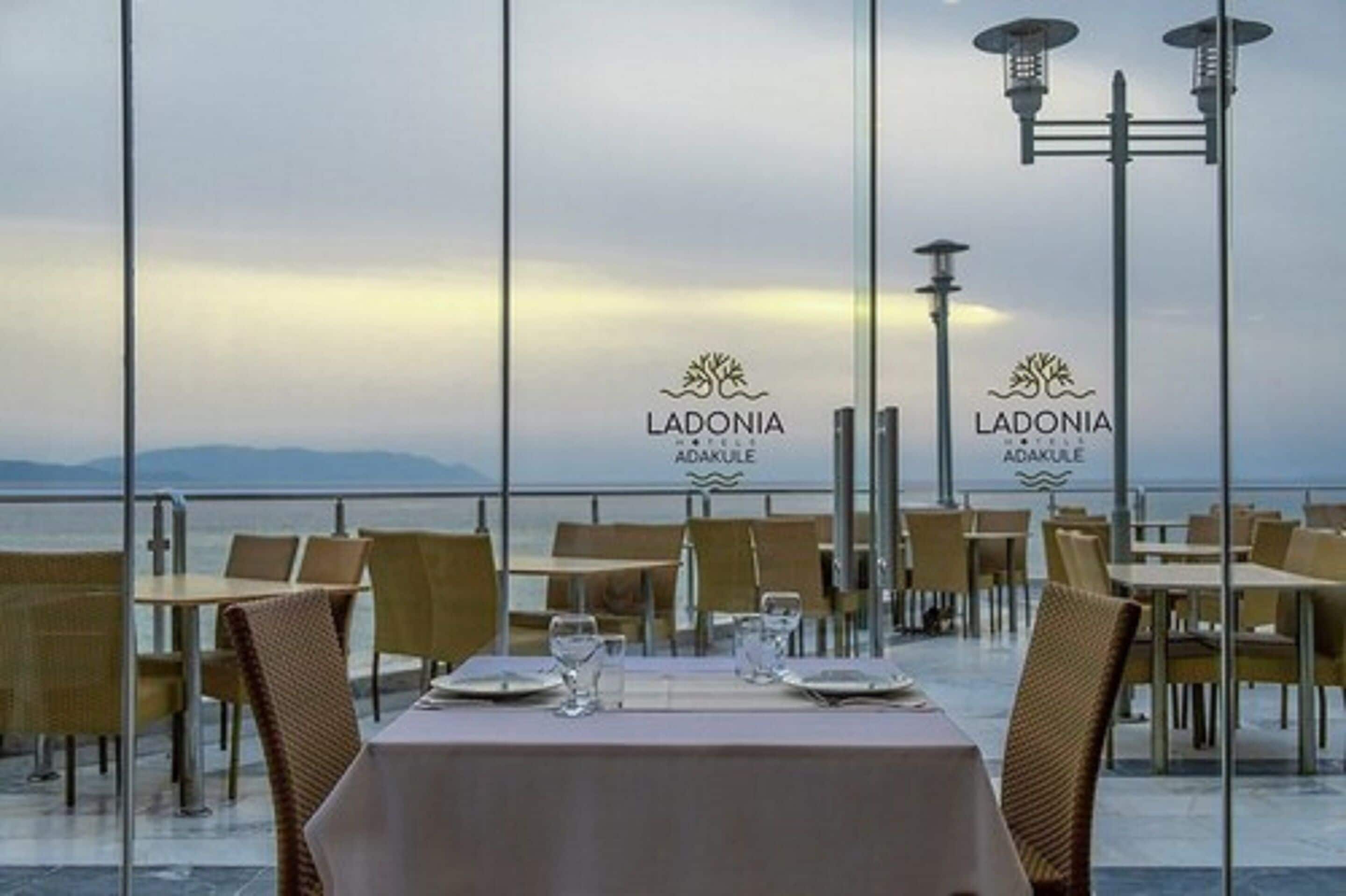 A dining area with tables set for two, overlooking a body of water.