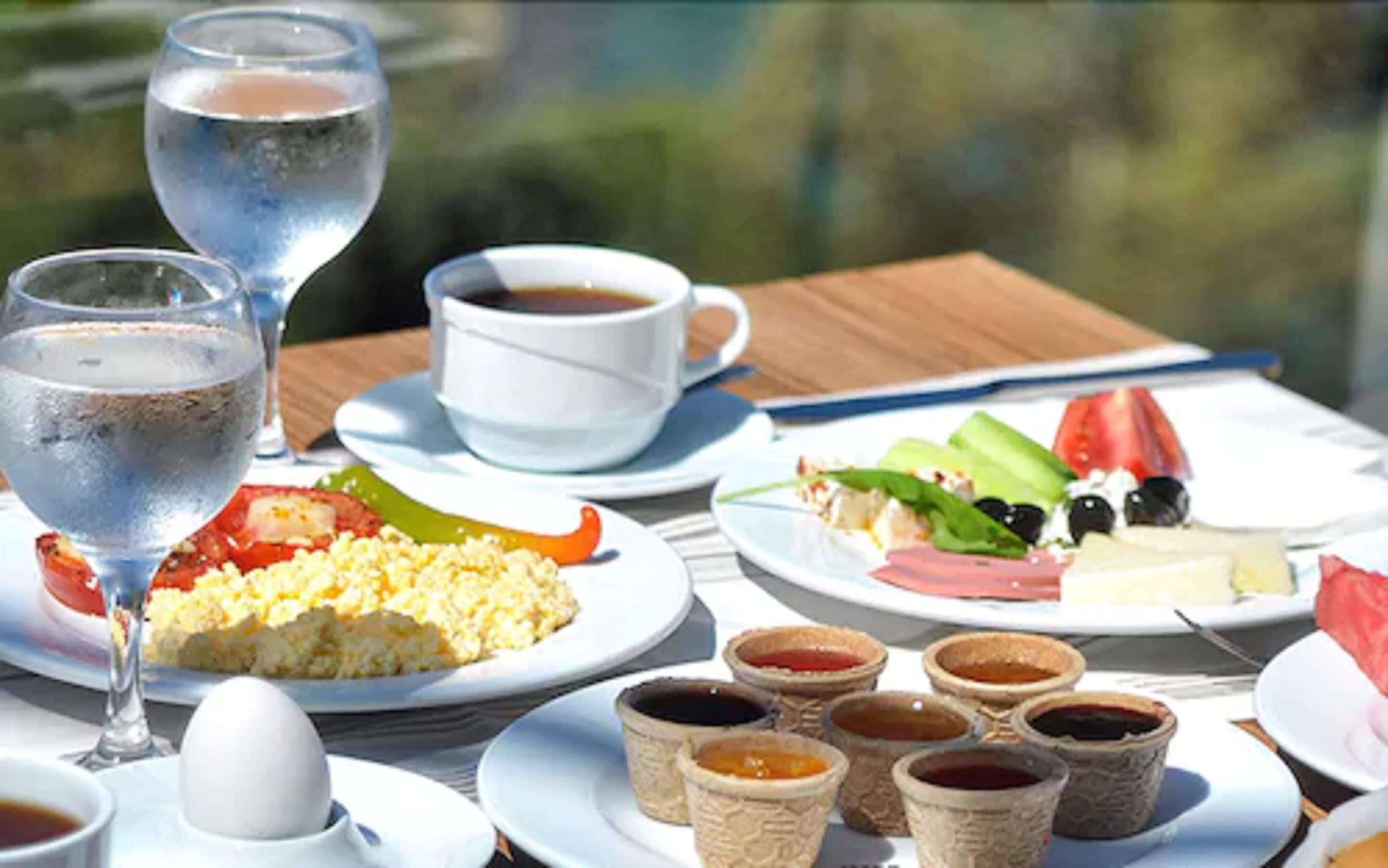 A table set with breakfast items including scrambled eggs, toast, and a variety of spreads in small containers.