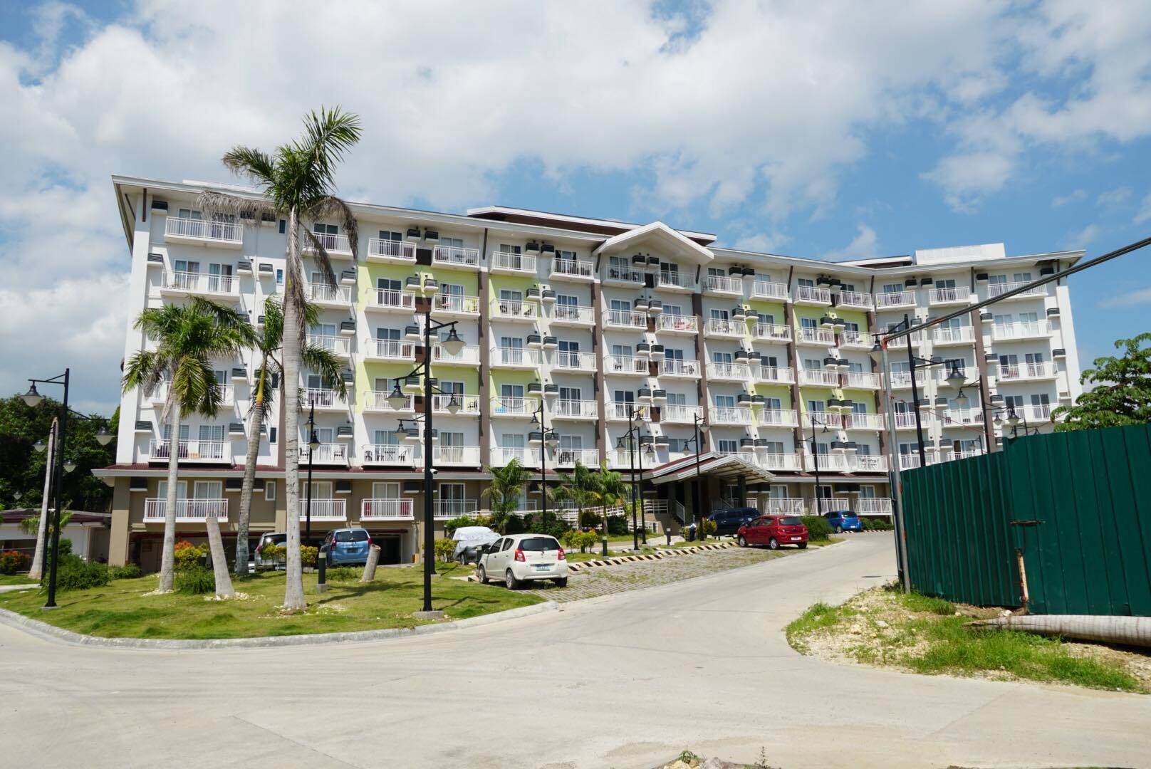 A multi-story hotel with balconies, a covered entrance, and a parking area.