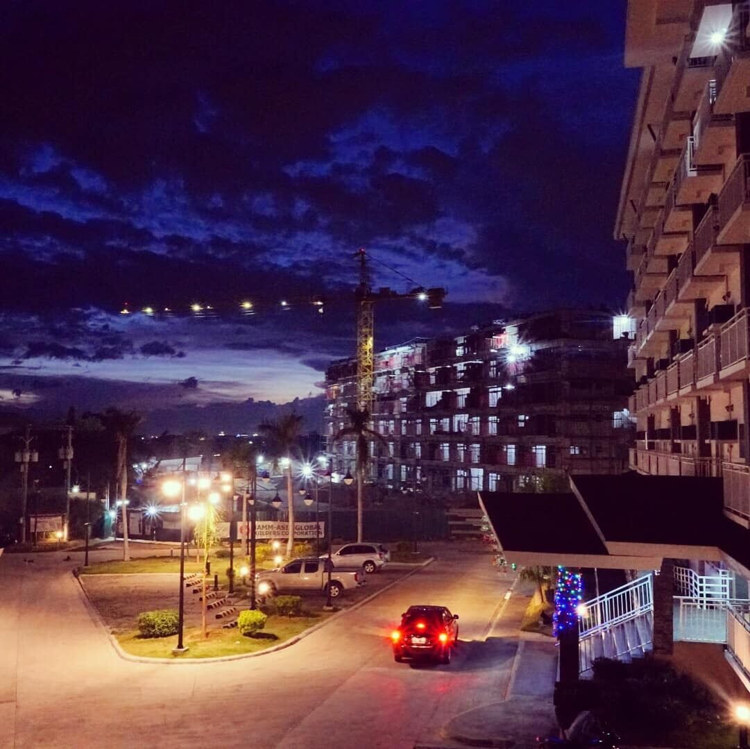 A nighttime view of a multi-story building with a parking lot in front.