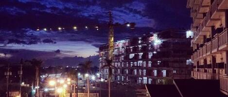 A nighttime view of a multi-story building with a parking lot in front.