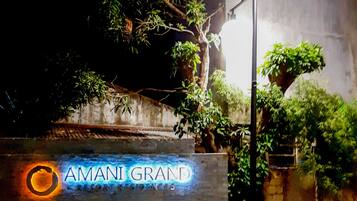 A nighttime view of a building entrance with a sign reading "AMANI GRAND SHOPPING CENTER".