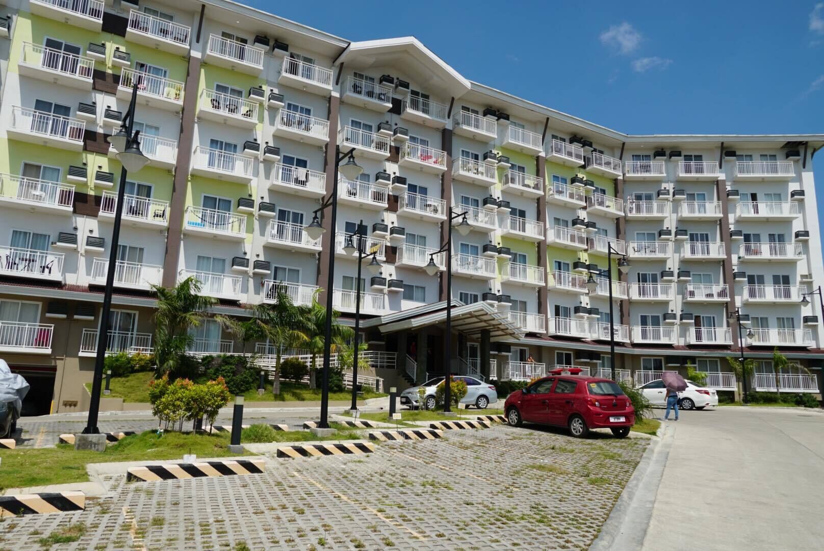 A multi-story hotel with balconies, a covered entrance, and a paved driveway.