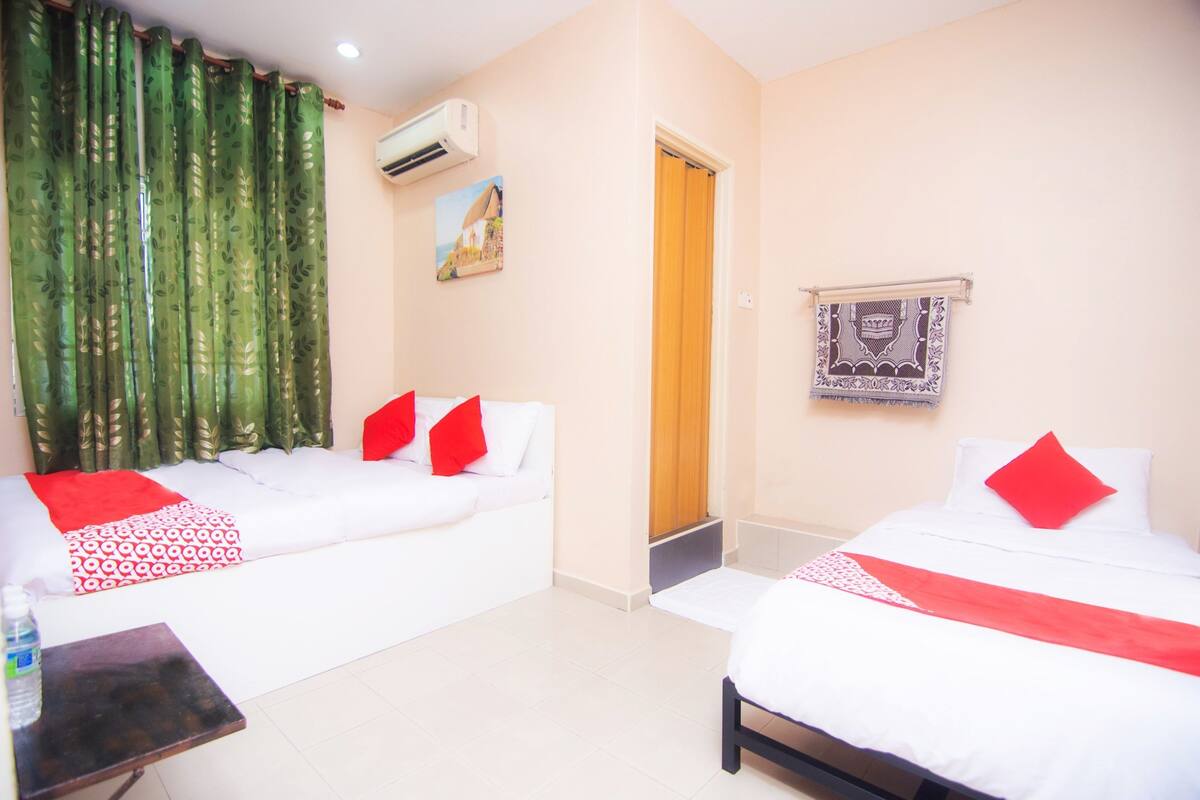 A hotel room with two beds, a small table, a water bottle, a painting, and a patterned tapestry.