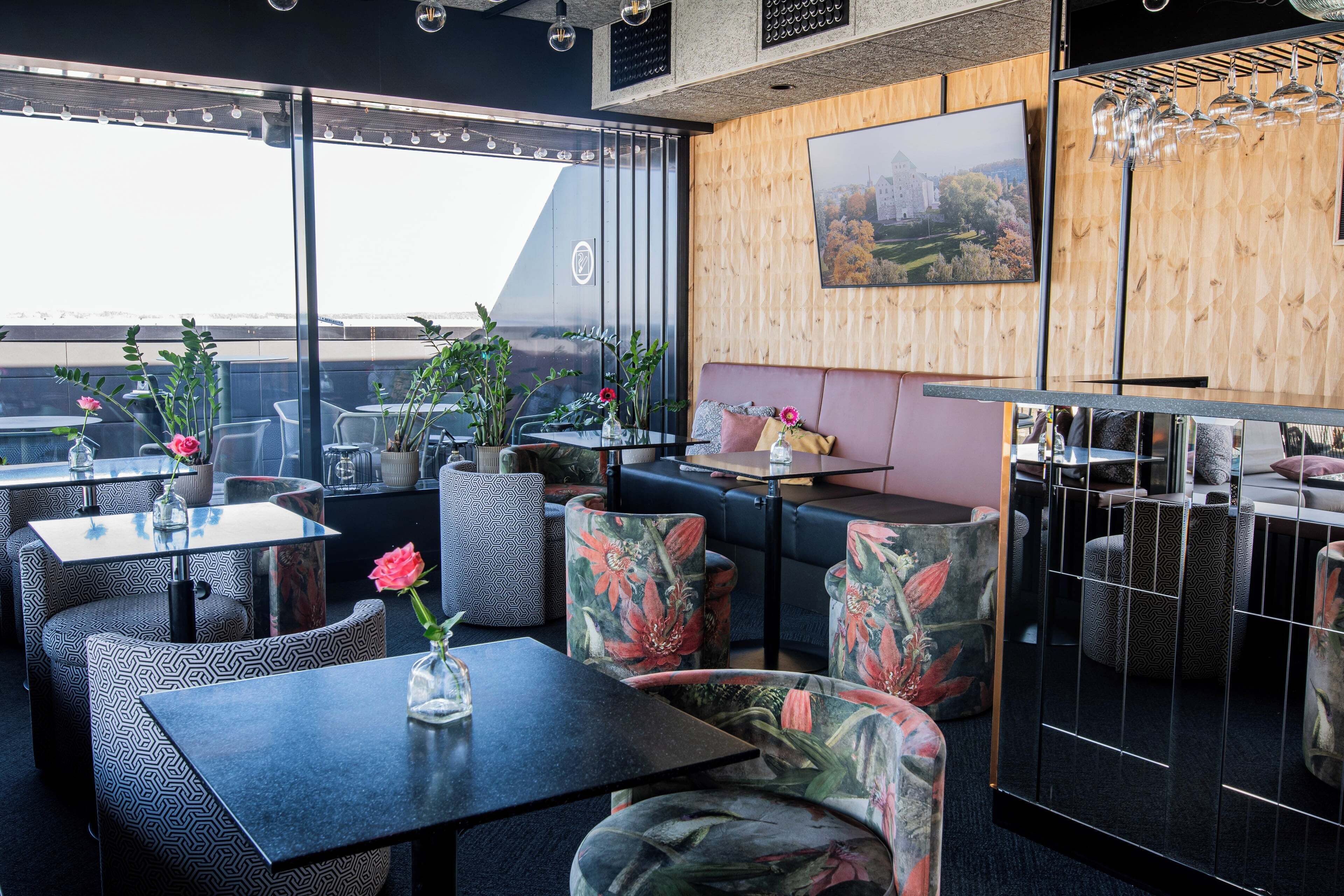 Ein modernes Interieur mit Sitzgelegenheiten, Tischen und einem großen Fenster mit Blick.
