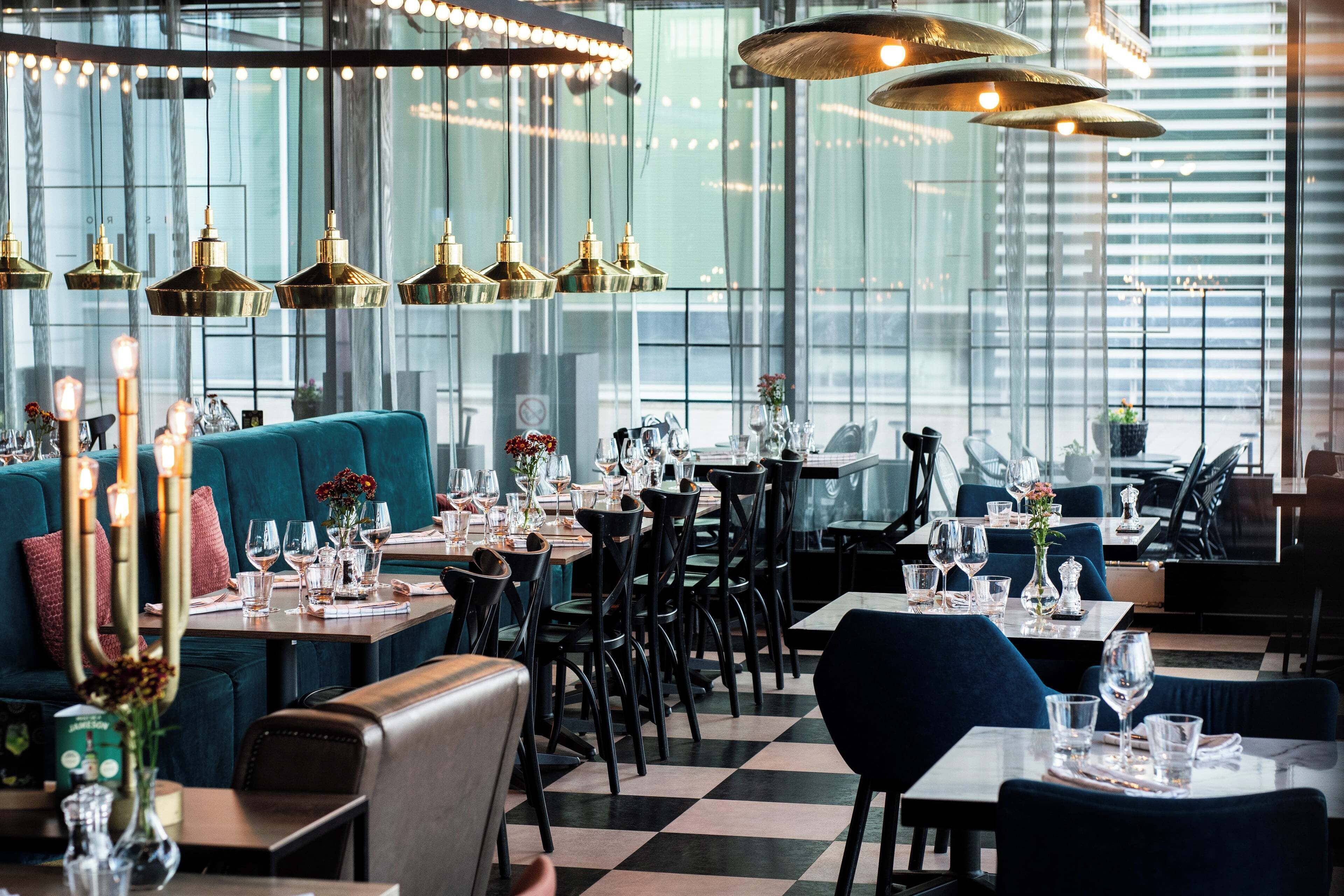 En restaurant med borde til spisning, et barområde og en siddekrog.