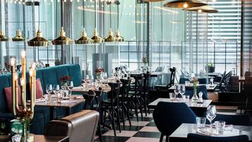 En restaurant med borde til spisning, et barområde og en siddekrog.