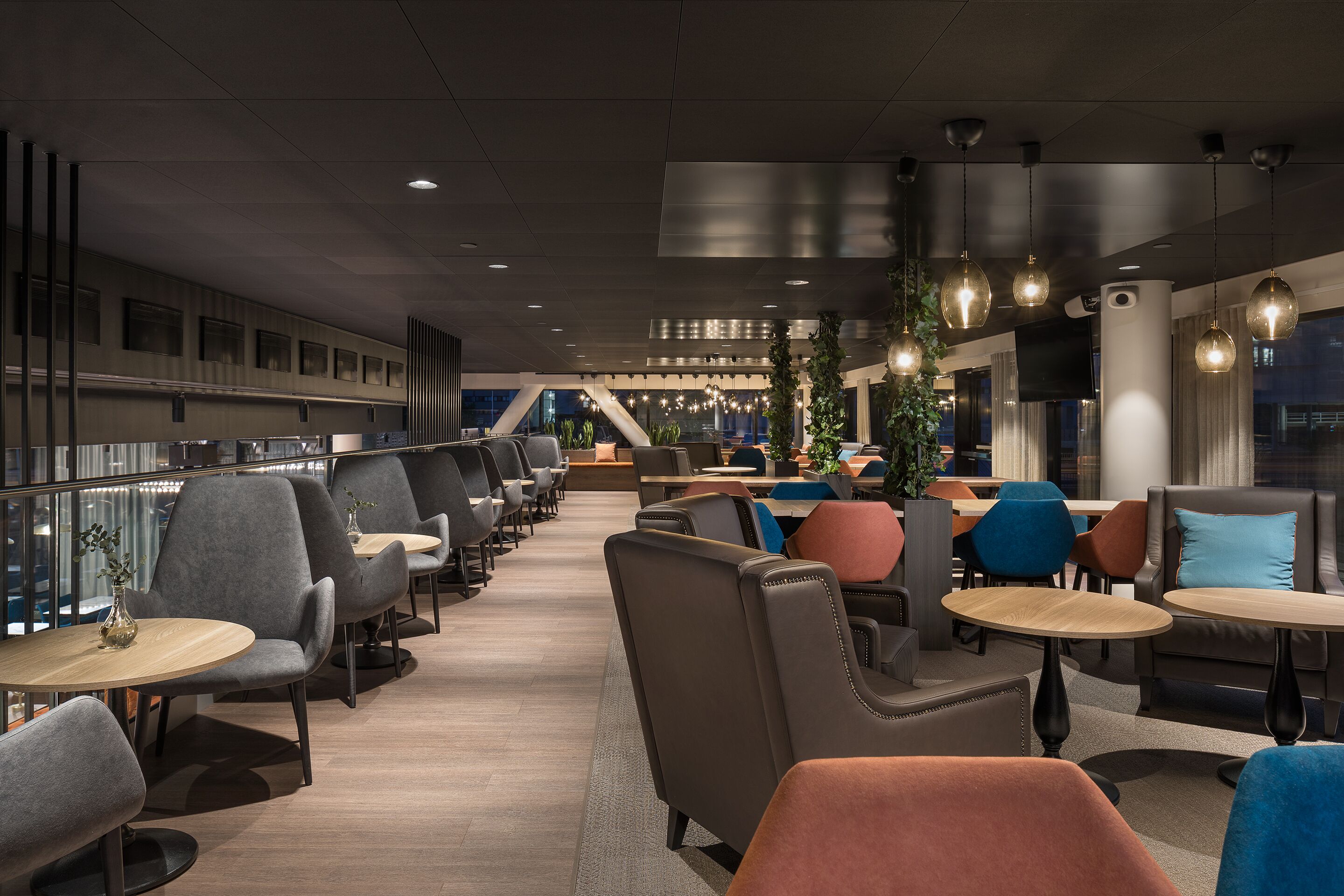 A modern lounge area with seating arrangements, tables, and hanging pendant lights.