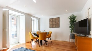 A modern dining area with a wooden floor, yellow chairs, and a dining table set for four. - Cozy & Stylish central apt in XIX century building (Lisboa)