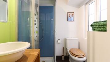 Un baño pequeño con ducha, inodoro y lavamanos.