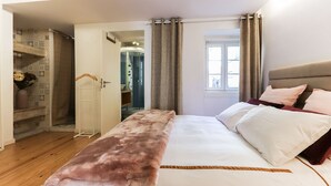Ein Schlafzimmer mit Bett, Nachttisch, Kleiderschrank, Spiegel und einer Duschkabine.