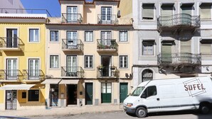 A white delivery van parked in front of a row of colorful buildings with balconies. - Cozy & Stylish central apt in XIX century building (Lisboa)