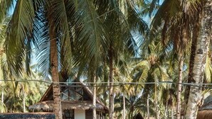 A tropical setting with thatched-roof huts, palm trees, and a hammock. - Secret Spot Siargao - Hostel (General Luna)