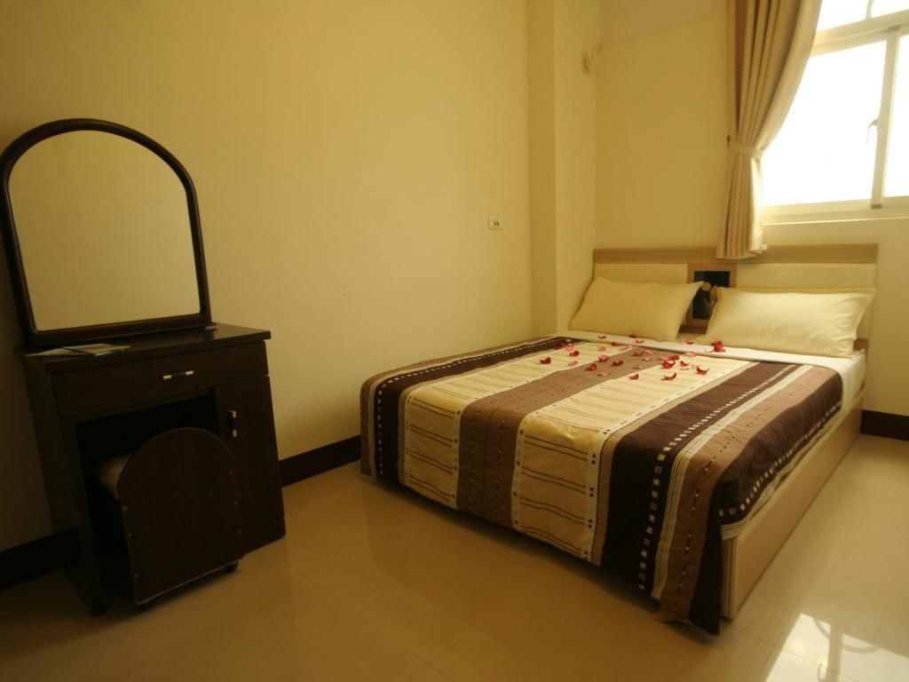 A bedroom with a bed, a dresser with a mirror, and a window with curtains.