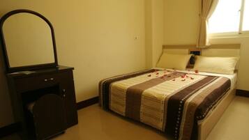 A bedroom with a bed, a dresser with a mirror, and a window with curtains.