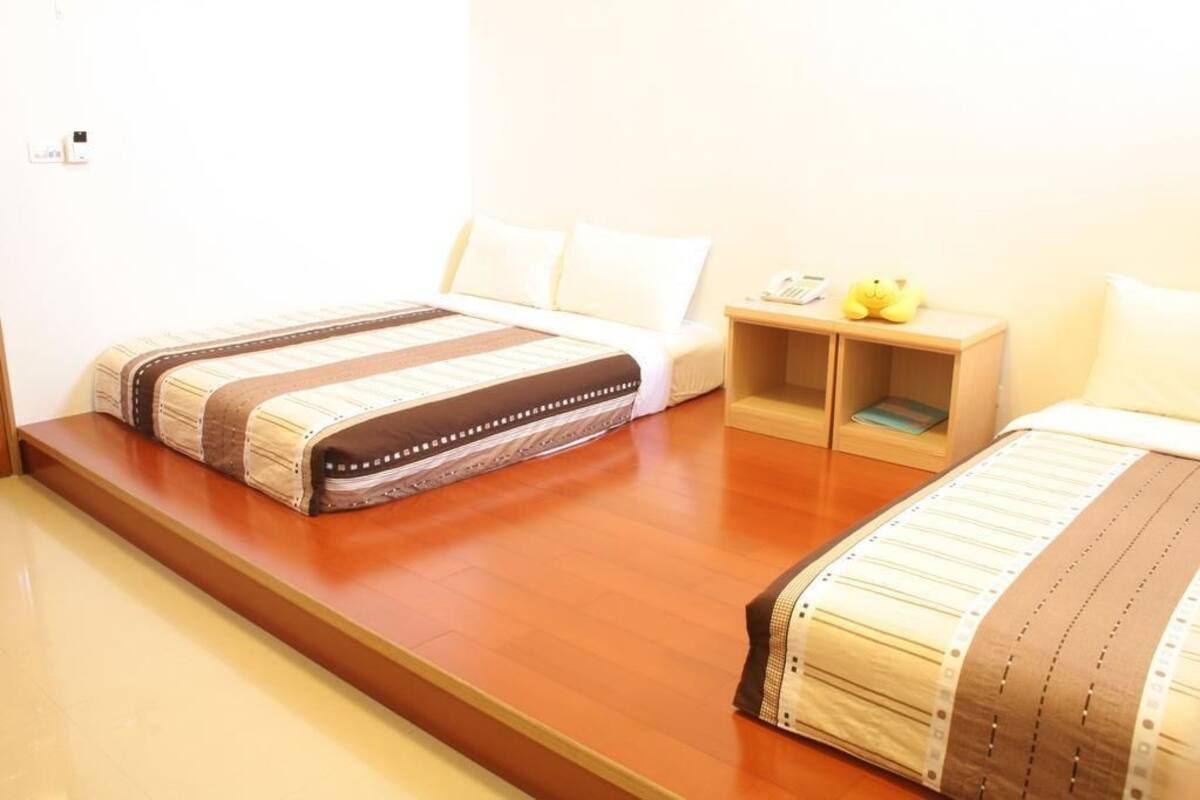 A hotel room with two beds, a wooden nightstand, and a small table.