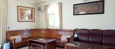 Una sala de estar con un sofá de madera, un sofá de cuero y una mesa de centro.