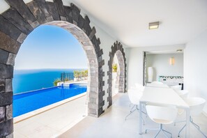 Une chambre moderne avec piscine, des arches en pierre et vue sur la mer.