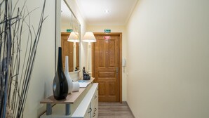 Un couloir avec une porte en bois portant l’inscription « SAIDA », un comptoir d’accueil orné d’un vase et d’une lampe, et un miroir qui reflète la porte.