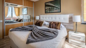 Une chambre d’hôtel moderne avec un grand lit, un miroir, un tableau et une table de chevet.