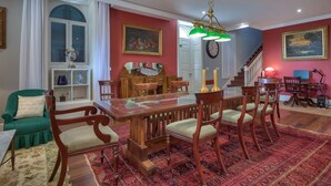 Un coin repas avec une table et des chaises en bois, une moquette rouge et un escalier en arrière-plan.