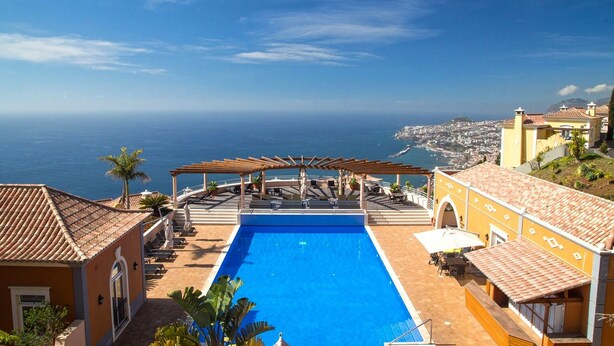 A rooftop pool with a view of the ocean, surrounded by buildings with terracotta roofs. - Dream Luxury Apartment  Palheiro Village (Funchal)