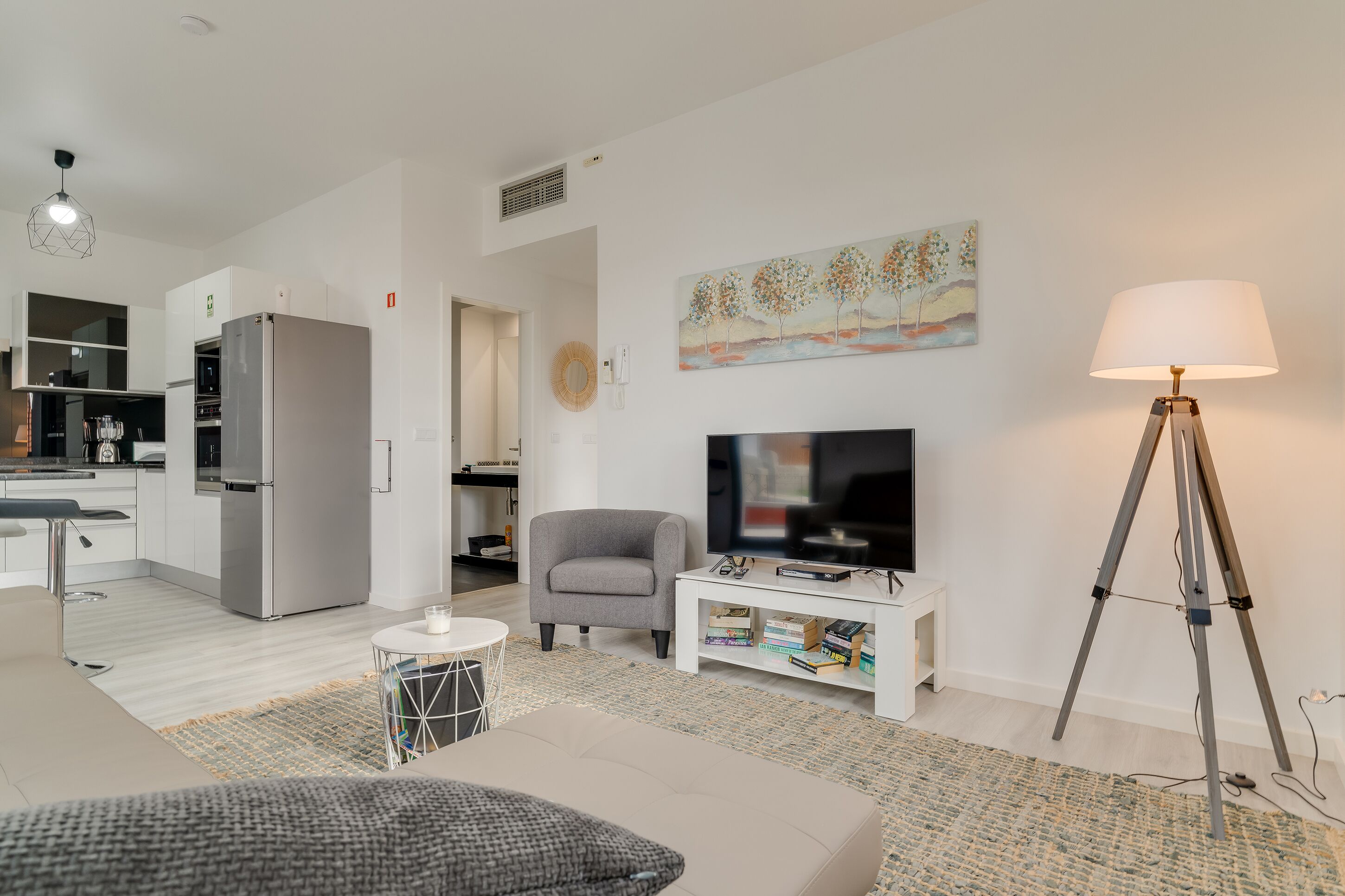A modern living room with a grey sofa, a white coffee table, a television, and a floor lamp.