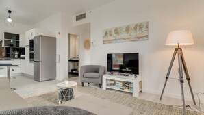 A modern living room with a grey sofa, a white coffee table, a television, and a floor lamp. - Lazareto Apartment (Funchal)