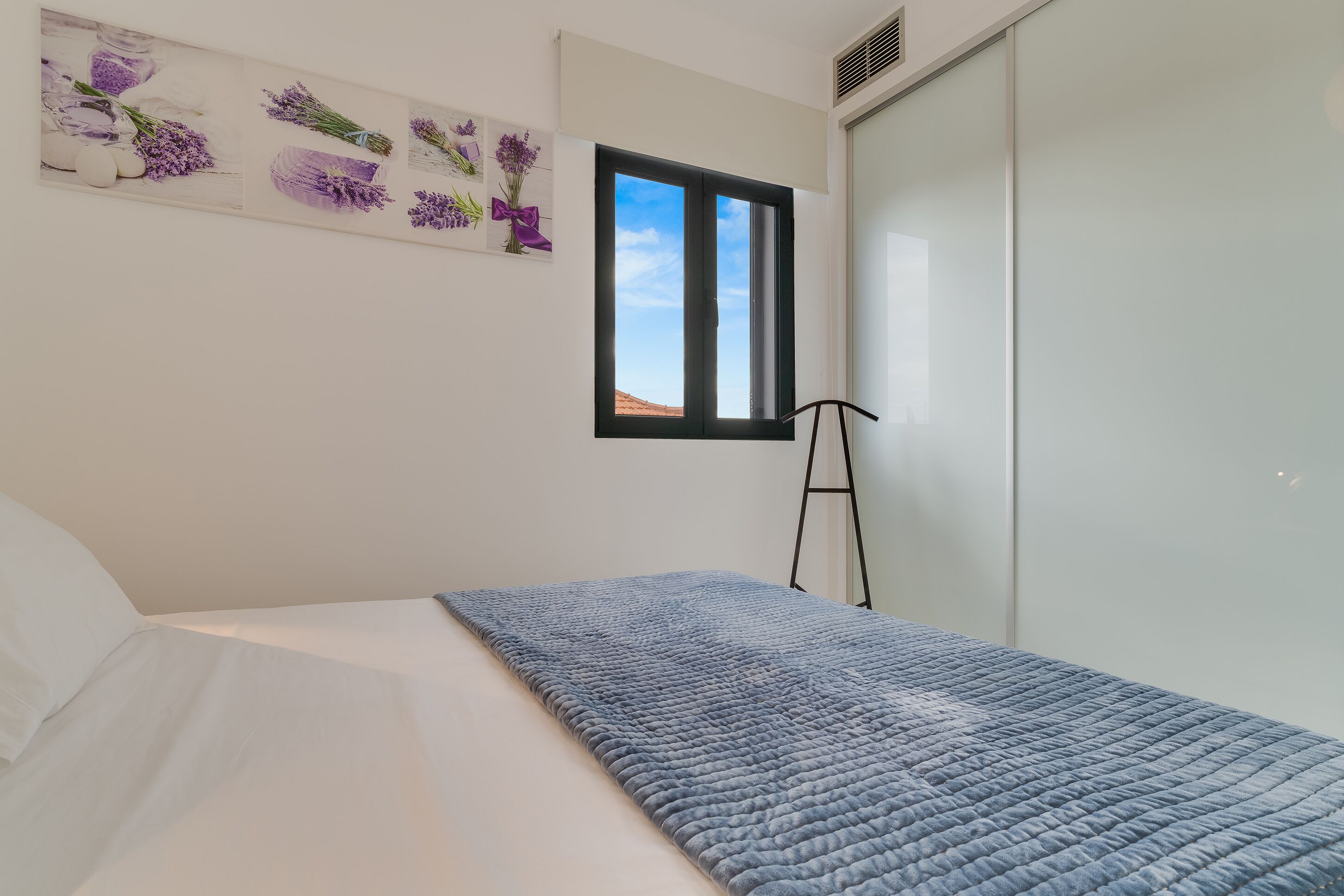 Una camera da letto con un letto, una finestra, una scala e un muro decorato con motivi floreali.