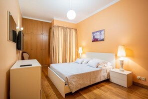 Ein Hotelzimmer mit Bett, Nachttischen, Schreibtisch, Fernseher und Kleiderschrank.